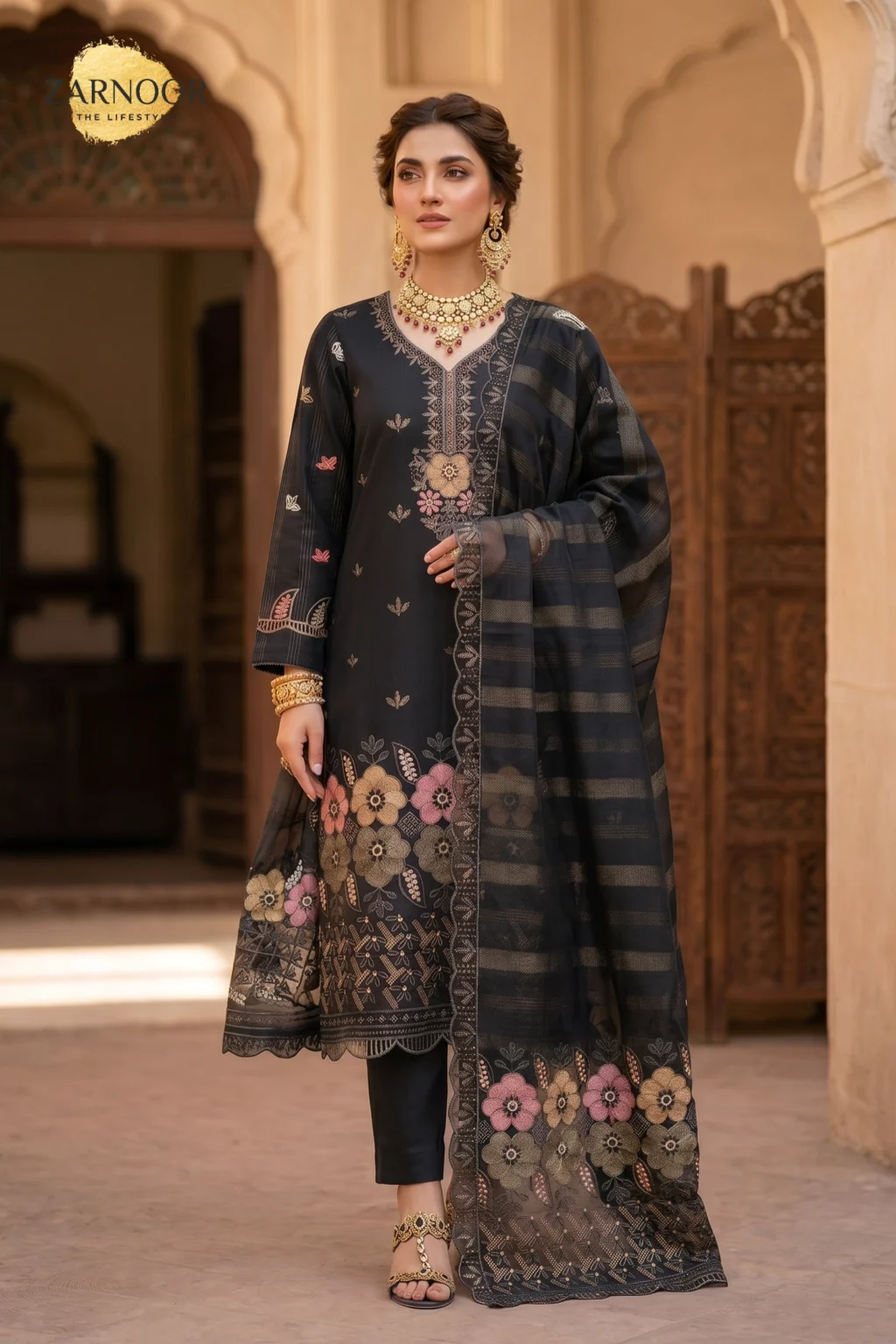 Woman wearing black 4 piece suit with Chamki embroidery, boring daman detailing, matching dupatta, and dyed cotton trousers